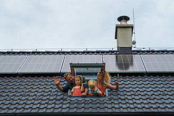 Happy family waving from skylight window in their new house with solar panels on the roof....