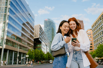 Two young beautiful smiling girls looking on the phone together