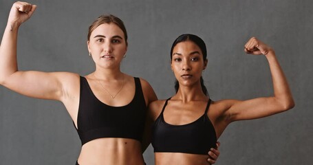 Two female friends flexing their arm muscles after gym