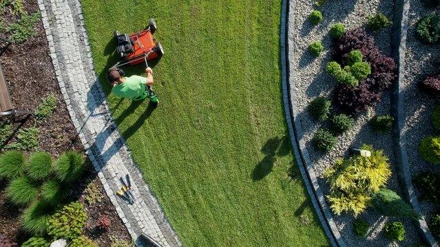 Powerful Gasoline Lawn Aerator Job For Controlling Lawn Thatch, And Reducing Soil Compaction. Backyard Grass Field Maintenance. Caucasian Gardener in His 40s. Aerial View.