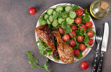 Baked chicken drumsticks with cherry tomato, cucumber and arugula salad, Top view
