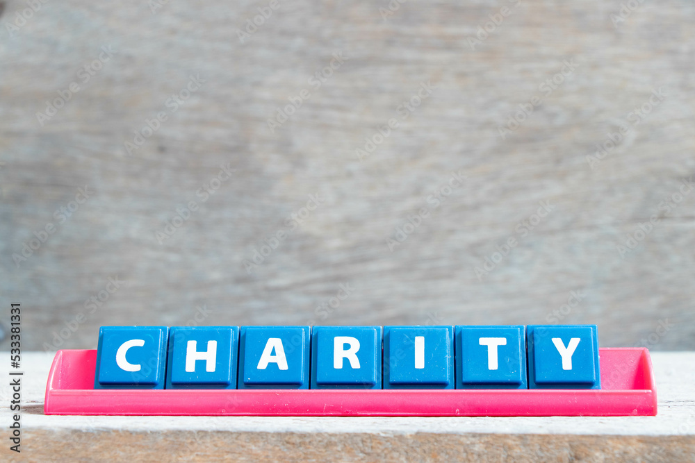 Sticker Tile alphabet letter with word charity in red color rack on wood background