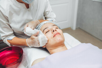 Obraz na płótnie Canvas A cosmetologist cleanses the skin of a beauty salon client before the procedure and facial massage. The concept of beauty and health. cosmetology.