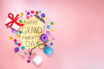 Obraz na płótnie Canvas Happy Grandparents day greeting card background. Granny and grandpa's day celebration, with gift boxes, knitting threads, buttons, glasses, decor top view copy space