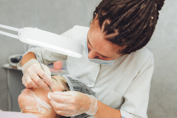 Cosmetic facial cleansing procedure for a young woman using a spoon uno. acne treatment. mechanical cleaning of the facial skin.