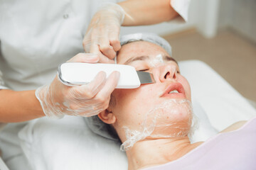 Obraz na płótnie Canvas Ultrasonic cosmetic scrubber. Facial cavitation procedure. Salon skin care procedure. Professional hardware peeling. Acne removal. contaminated person