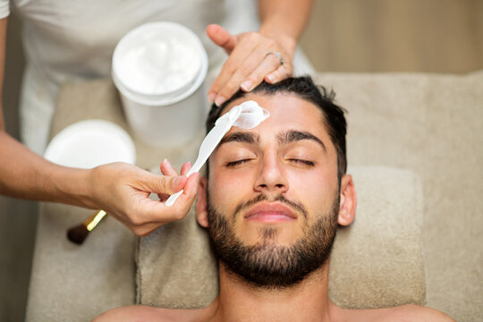 Cosmetician doing purifying face treatment for man