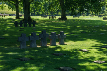 Black crosses of graves under trees at German Military Cemetery and Memorial at La Cambe, Normandy, France.