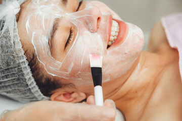 Fototapeta premium A cosmetologist does facial care and apply a face mask. cleansing a heavily soiled face. acne on the skin. skin rashes. mechanical face painting.