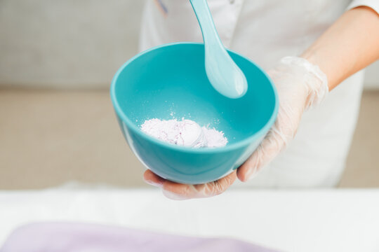 A cosmetologist prepares a lilac alginate mask in Minsk. Alginate mask for the skin. Cosmetology. Skin care procedure. Cosmetologist prepares a rejuvenating mask