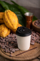 Takeaway White paper hot cocoa cup on Ripe cocoa pod and nibs, cocoa beans set up background