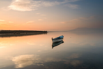 Naklejka premium Fishers boats on the lake, calm water with beautiful reflection of colorful sky tranquily scene