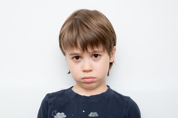 Portrait of a child in a bad mood close-up isolated on a white background. Offended little boy...