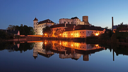 Jindrichuv Hradec Castle and Chateau, beautiful landmark mirroring in pond during night after sunset, popular tourist destination Jindrichuv Hradec, Czechia