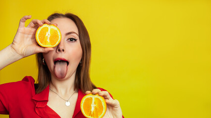 Portrait of a Caucasian girl with a radiant clean skin holding orange halves isolated on a yellow background. The concept of cosmetics with vitamin C. A place for your advertising or text.