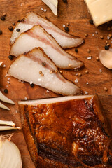 still life of food in a rural style on a dark wood background, sliced lard and garlic, cheese and onion, concept of fresh vegetables and healthy food