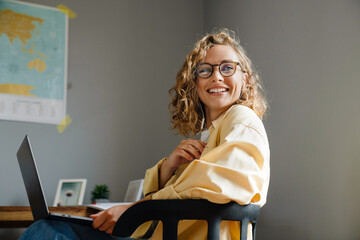 Young beautiful smiling woman in glasses with laptop looking aside