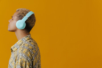 Blonde young man wearing shirt in headphones listening music