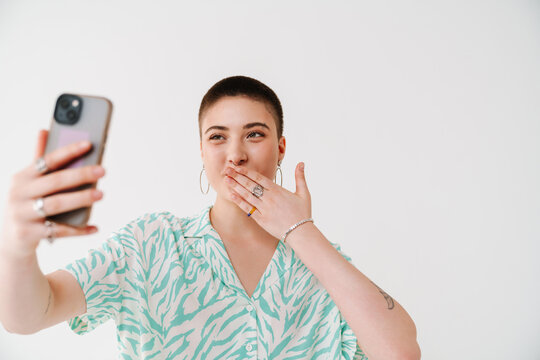 Young woman gesturing and taking selfie photo on cellphone