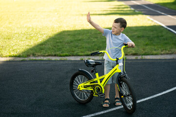 cheerful boy with bicycle waving hand, space for text, sport childhood concept 
