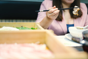 Asian woman using chopsticks to put food into her mouth