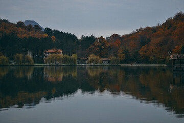 Fototapeta premium Luxury hotel in a nature park in autumn, Dense Smoke Rises From the Chimney. House by the lake in autumn, bike path near the lake, Recreation walk, and cycle path road sign. 