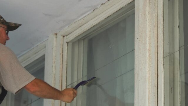 A man window cleaner cleans a window with a silicone or rubber scraper