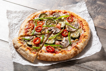 Vegetarian pizza with zucchini, tomato, peppers and mushrooms on wooden table