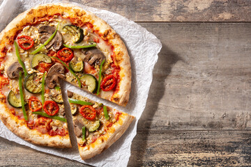 Vegetarian pizza with zucchini, tomato, peppers and mushrooms on wooden table. Copy space