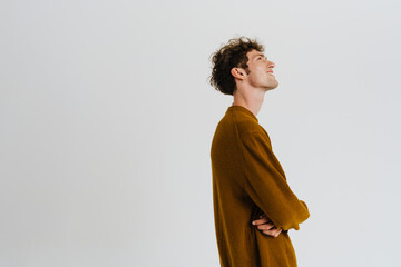 Young handsome curly, smiling man in sweater with folded arms