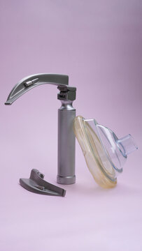 intubation set: laryngoscope and endotracheal tubes for the ventilator lie on a pink background. close up, postcard, medical instruments, anesthesiology