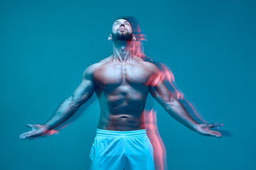 Strong powerful athlete sportive man with muscular naked body looks up. Long exposure. Neon studio...
