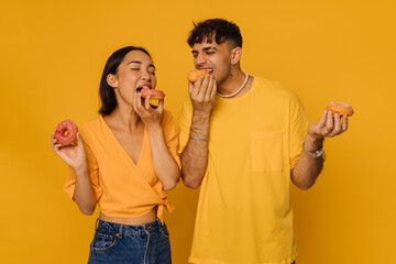 Young asian woman and man eating donuts with closed eyes