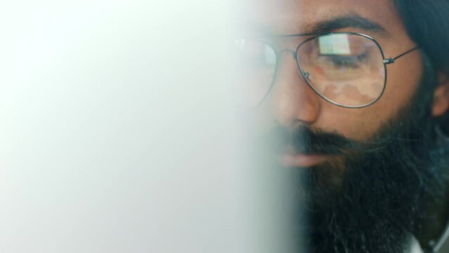 Information technology, programming and an Indian man coding on a computer with glasses. Software developer, web designer or programmer working on online project for cybersecurity for a data company.