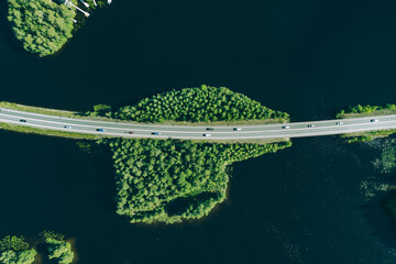 Aerial view of road through blue lakes or sea with green woods in Finland.