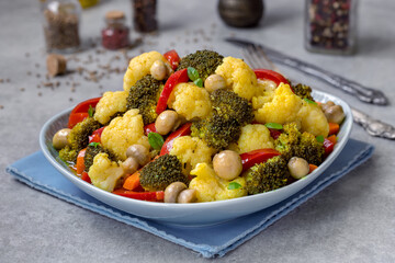 Colorful marinated broccoli and cauliflower salad with red bell pepper, carrot, small white button...