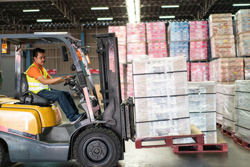 Asian male driver driving forklift loading parcel box to shipping delivery in the warehouse...