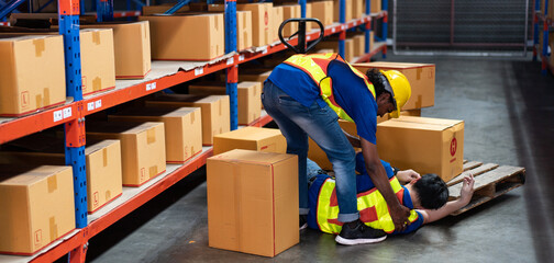 Warehouse factory worker helping to pick up colleague, Parcel box falls from the shelves to hit...