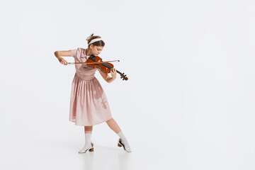 Charming beautiful young girl playing violin isolated over white studio background. Tender, lovely...