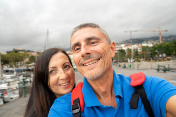 Fototapeta na wymiar Happy couple taking selfies in a beautiful island small port
