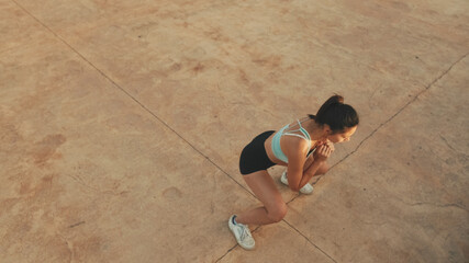 Fototapeta na wymiar Asian girl in sports top does workout, stretching and gymnastics at morning time. View from above