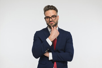 thoughtful young businessman with glasses touching chin and thinking