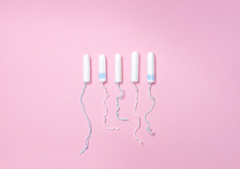 Many sanitary tampons lie in a row on a light pink background. Menstrual cycle and pregnancy. Negative pregnancy test and contraceptives