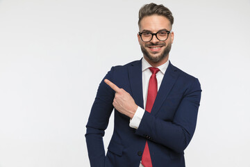 happy young businessman with glasses pointing finger to side