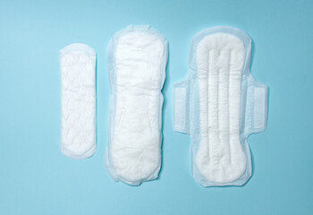 Sanitary pads are lying on a light blue background. Menstrual cycle and pregnancy. Negative pregnancy test and contraceptives