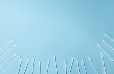 Many white cotton buds on a light blue background. Ear stick and cotton swab for cosmetology and hygiene