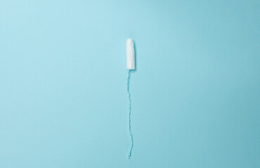 A sanitary tampon lies on a light blue background. Menstrual cycle and pregnancy.