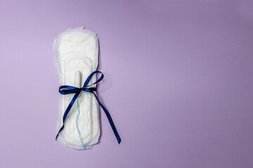 Sanitary tampon and pads lie on a purple background with a blue bow. Menstrual cycle and pregnancy. Negative pregnancy test and contraceptives