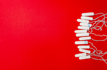 Many sanitary tampons lie on a red background. Menstrual cycle and pregnancy. Negative pregnancy test and contraceptives