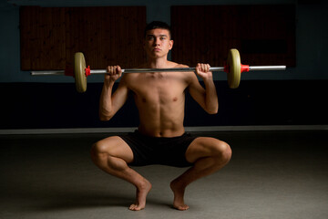 Fototapeta na wymiar Nineteen year old teen boy exercising with a barbell shirtless